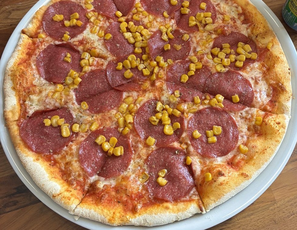 Salami-Pizza mit Mais, frisch aufgeschnitten