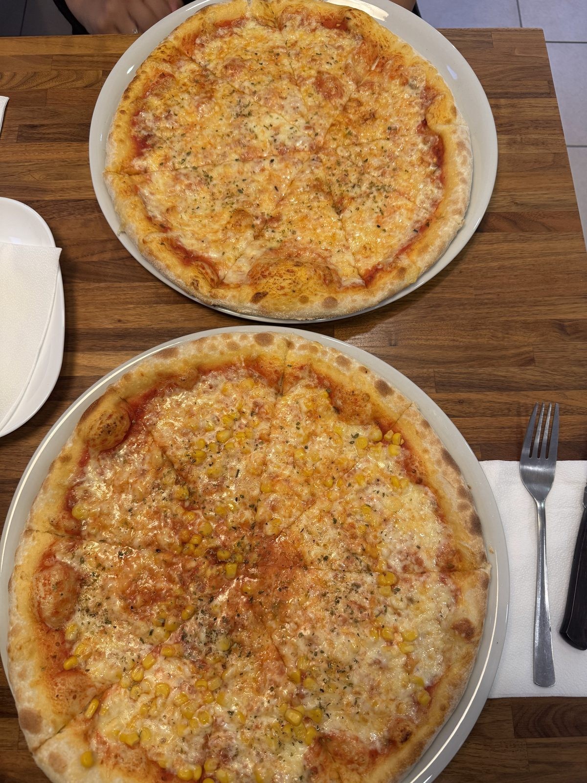 Zwei frisch gebackene Pizzen aus dem Steinofen – Margherita und Mais